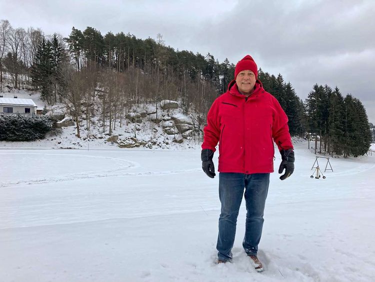 Der sozialdemokratische Gemeinderat Herbert Kraus steht mit roter Jacke und roter Mütze vor einer verschneiten Wiese