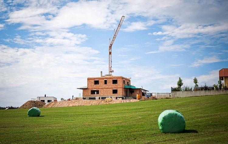 Baustelle eines Einfamilienhauses auf einer grünen Wiese.