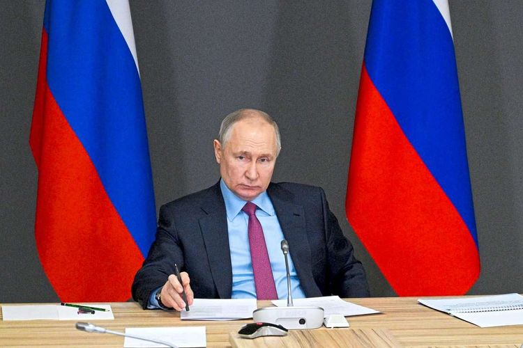 Russlands Präsident Wladimir Putin, an einem Tisch sitzend.