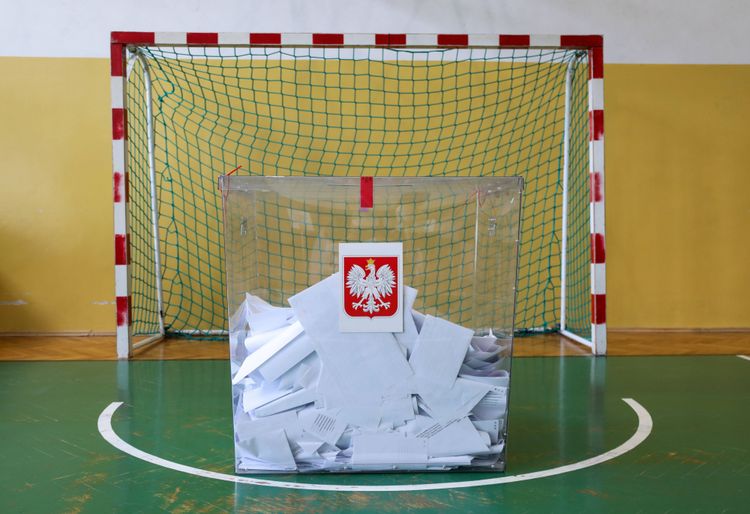 Wahlurne mit polnischem Wappen in einem Turnsaal, dahinter ein Fußballtor.