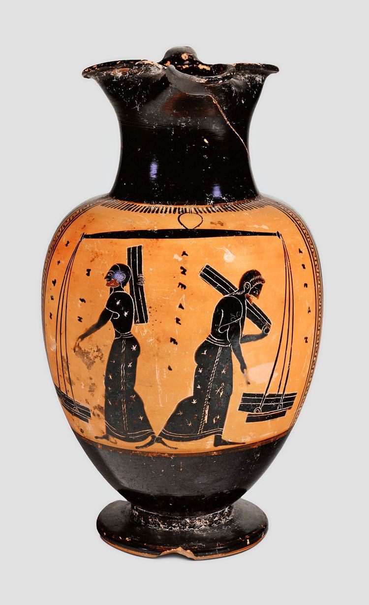Eine antike griechische Vase im schwarzfigurigen Stil mit zwei Frauenfiguren, die jeweils Holz und einen Joch tragen. Die Vase hat einen runden Fuß, einen bauchigen Körper und einen leicht nach außen gebogenen Hals. Verzierungen und Detailarbeit sind sichtbar.