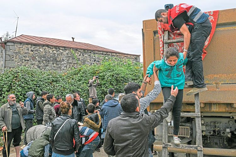 Flüchtlinge aus Bergkarabach steigen aus Lastwagen