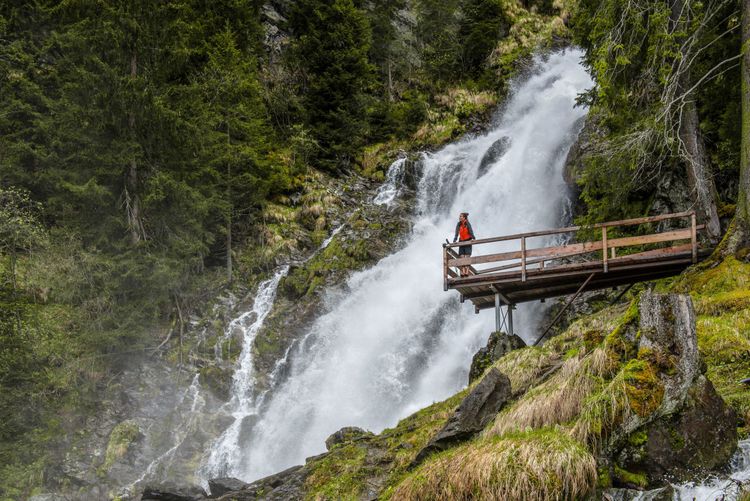 Mensch auf einer Aussichtsplattform über einem Wasserfall
