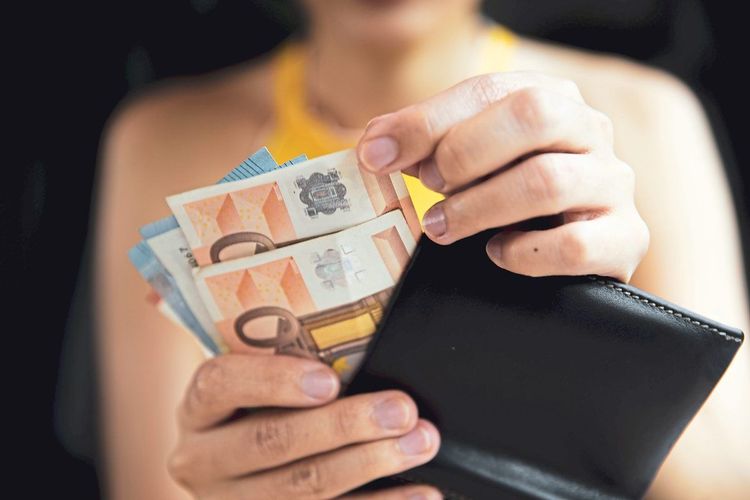 Junge Frau nimmt Geldscheine aus ihrer Geldbörse
