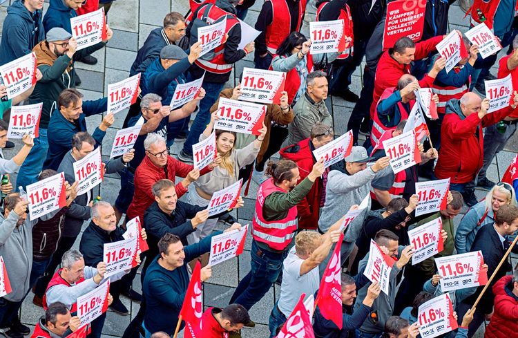 Menschenmenge. Viele halten ein Schild mit 