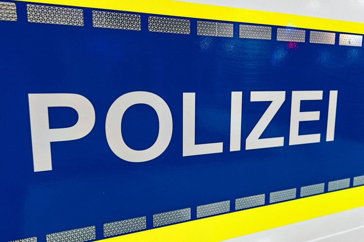 Blauer Hintergrund mit weißem Schriftzug „POLIZEI“, umrandet von gelben und reflektierenden Elementen.