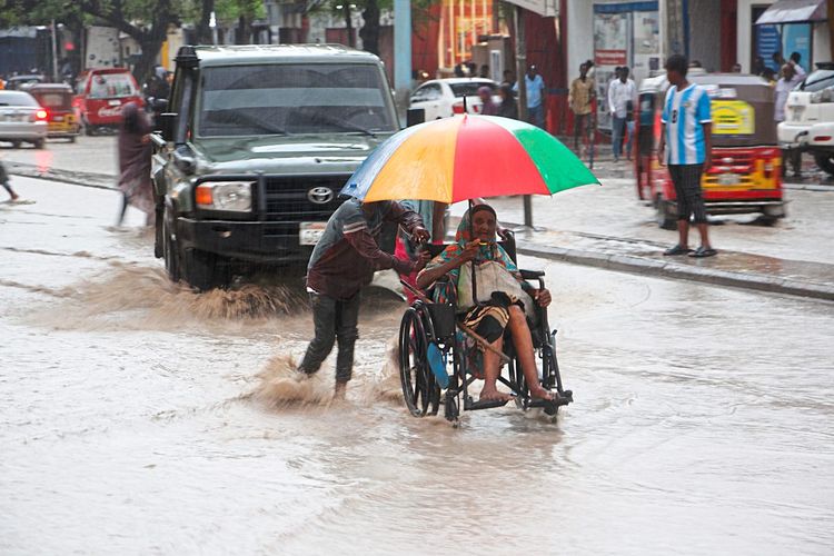 Eine Frau im Rollstuhl mit Regenschirm