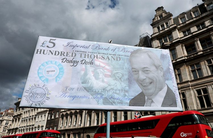 Ein Protestplakat mit einer satirischen Darstellung, die an eine Banknote erinnert und Kritik am Reform UK-Parteichef Nigel Farage sowie mögliche illegale Parteispenden äußert, ist nahe den Houses of Parliament in London zu sehen. Im Hintergrund sind historische Gebäude und ein roter Doppeldeckerbus zu erkennen.