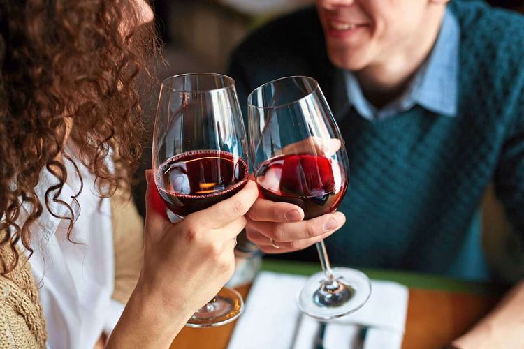 Paar stößt in einem Restaurant mit Rotweingläsern an