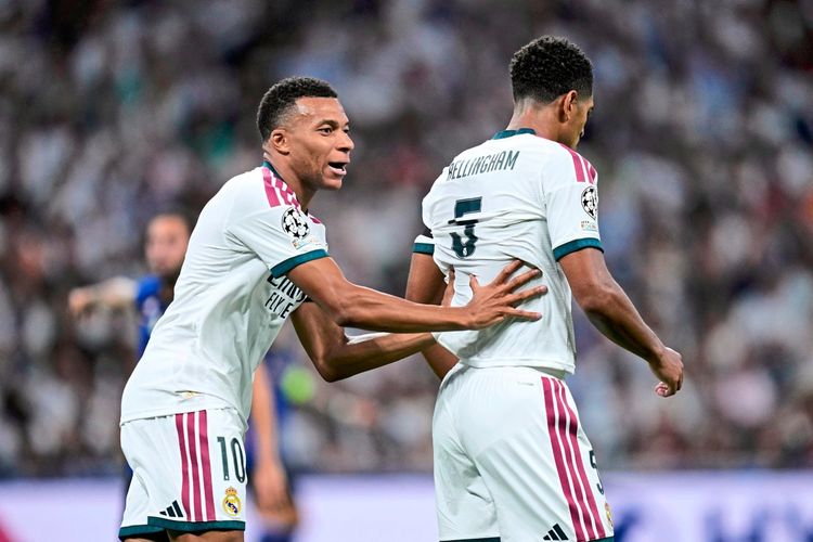 Zwei Fußballspieler von Real Madrid in weißen Trikots während eines Champions-League-Spiels im Santiago-Bernabéu-Stadion. Einer legt dem anderen die Hand auf den Rücken. Hintergrund unscharf mit Zuschauern.