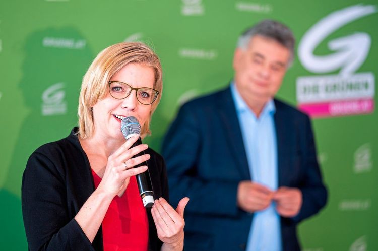 Ministerin Leonore Gewessler mit Mikrofon und im Hintergrund Vizekanzler Werner Kogler