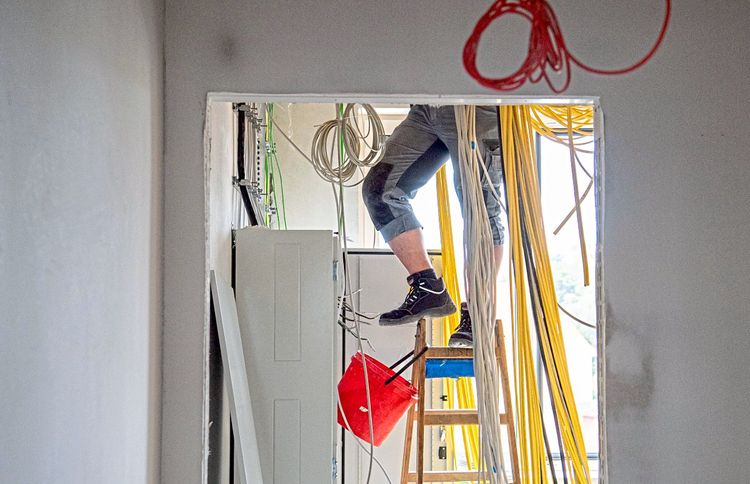 Ein Arbeiter steht auf einer Baustelle auf einer Leiter.