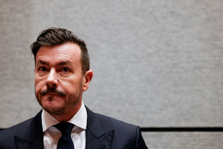 René Benko in dunklem Anzug und weißen Hemd, er schaut in die Kamera.