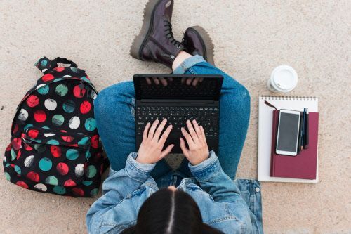 Junge Frau mit Laptop und Lernunterlagen