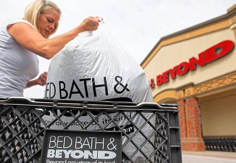 Eine Frau packt ihren Bed Bath & Beyond Sack in ein Einkaufswagerl