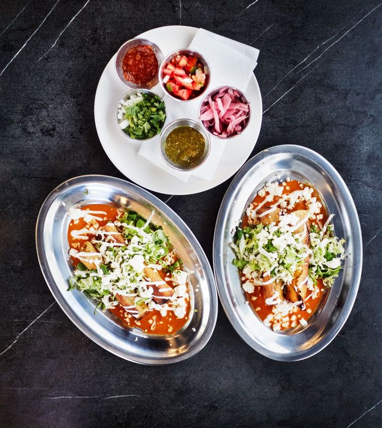 Flautas de Pollo, gerollte, frittierte Tortillas mit Hendl, Frischkäse und Salat gefüllt, in einer Salsa aus geräucherten Chilis. Darüber die Batterie diverser Salsas picantes.