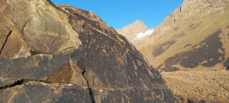 Fels in einem Tal in Tadschikistan, in den Schriftzeichen eingeritzt wurden.