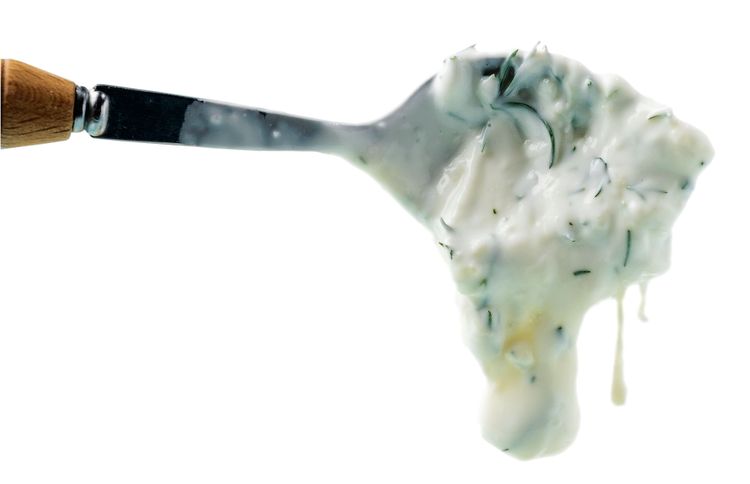 spoon with white sauce based on Greek yogurt, traditional tzatziki sauce, close-up 