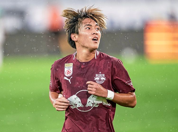 Ein Fußballspieler von Red Bull Salzburg im dunkelroten Trikot während eines Spiels, umgeben von leichtem Regen, auf einem grünen Spielfeld. Im Hintergrund ist ein unscharfer Stadionbereich zu sehen.