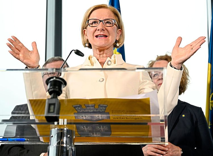 Die niederösterreichische Landeshauptfrau vor einem Rednerpult, die Hände erhoben im Reden erhoben