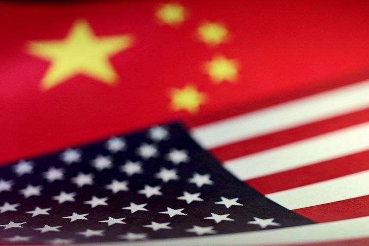 Nahaufnahme von zwei überlappenden Flaggen: der chinesischen Flagge oben mit gelben Sternen auf rotem Hintergrund und der US-amerikanischen Flagge unten mit weißen Sternen auf blauem Hintergrund und roten sowie weißen Streifen.