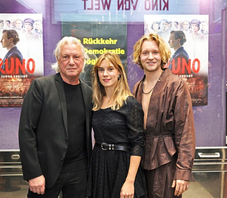 Drei Personen posieren vor Filmplakaten im Gartenbaukino in Wien bei der Premiere des Films 