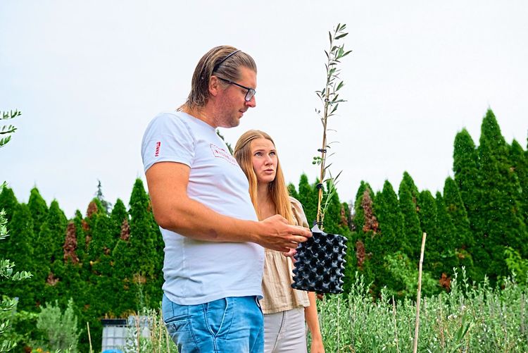 Ein Mann hält einen Topf mit Pflanze, daneben steht seine Frau.