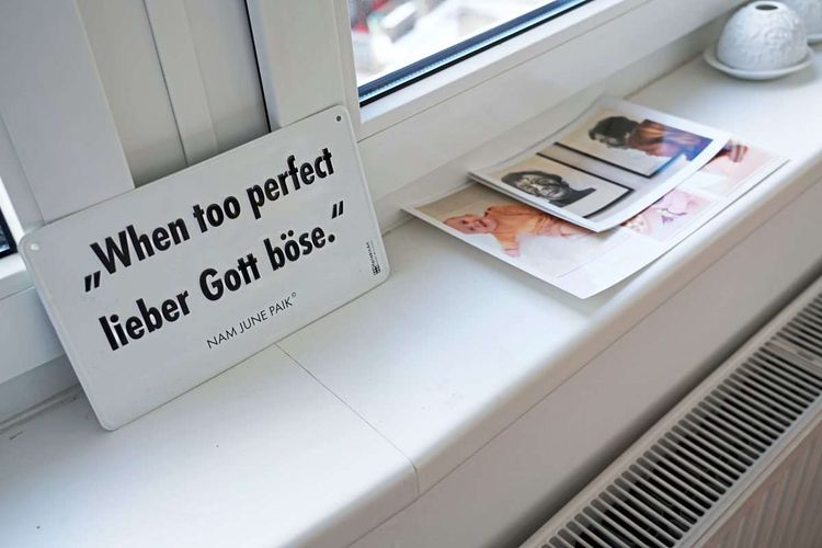 Auf einem Fensterbrett liegen Fotos von einer Ausstellung, daneben ein Schild mit der Aufschrift: 