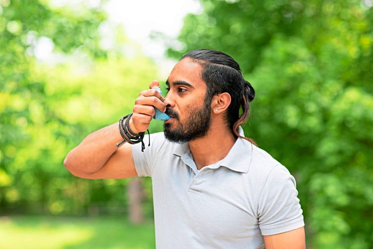 Junger Mann inhaliert Asthmaspray