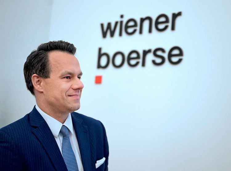 Christoph Boschan, Chef der Wiener Börse, steht vor dem Logo der Börse.