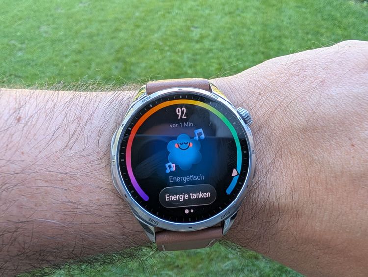 Ein buntes Smartwatchdisplay zeigt eine fröhliche Wolke und einen Energiescore.