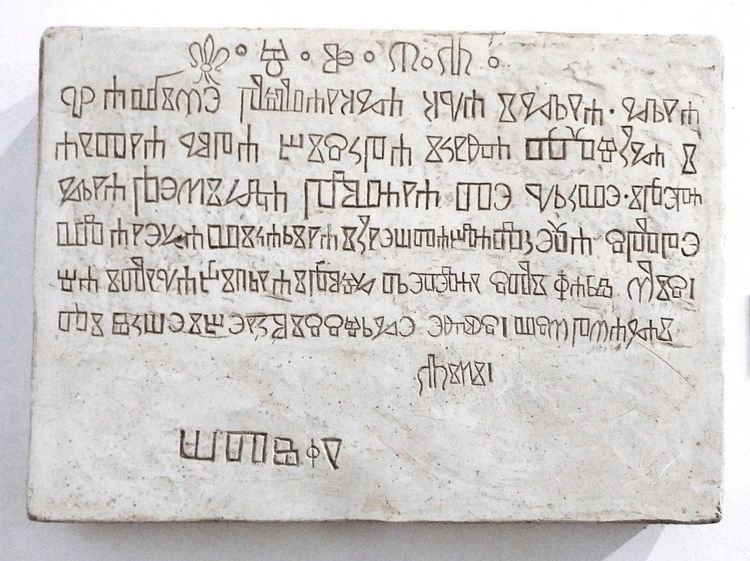 Eine weiße Steinplatte mit eingravierten Schriftzeichen in glagolitischer Schrift. Die Tafel stammt aus der Kirche des Heiligen Germanus auf der kroatischen Insel Brioni.