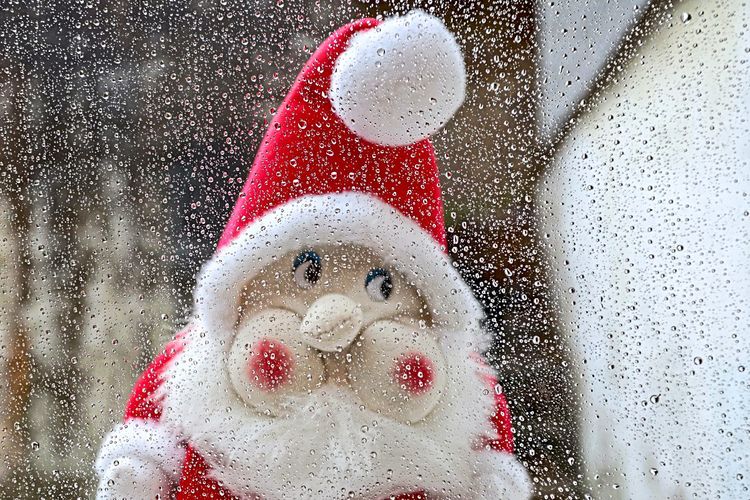 Weihnachtsmann blickt durch verregnete Scheibe.