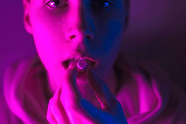 Teenager nimmt Pille, ausgeleuchtet in pinkem Licht