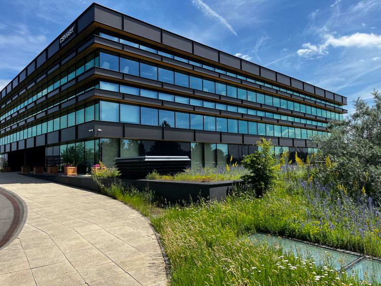 Moderner Glas-Stahlbau mit Grünpflanzen und blauem Himmel