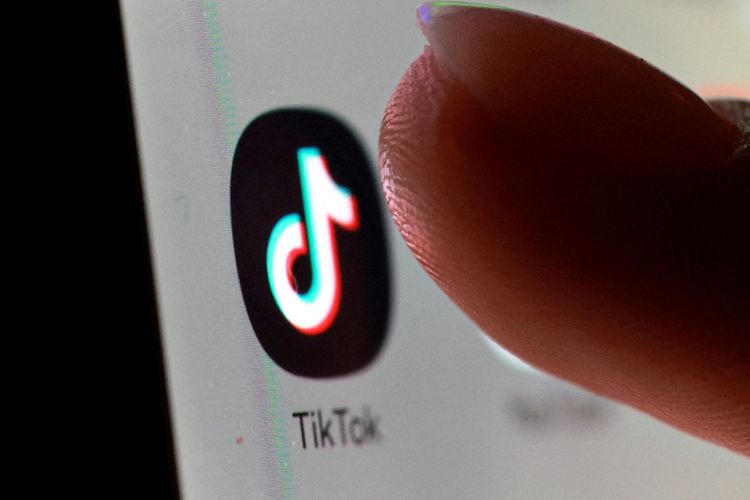 Nahaufnahme einer Fingerspitze, die kurz davor ist, das TikTok-App-Symbol auf dem Bildschirm eines Smartphones zu berühren. Das Symbol zeigt eine stilisierte Musiknote in Schwarz mit farbigen Akzenten.