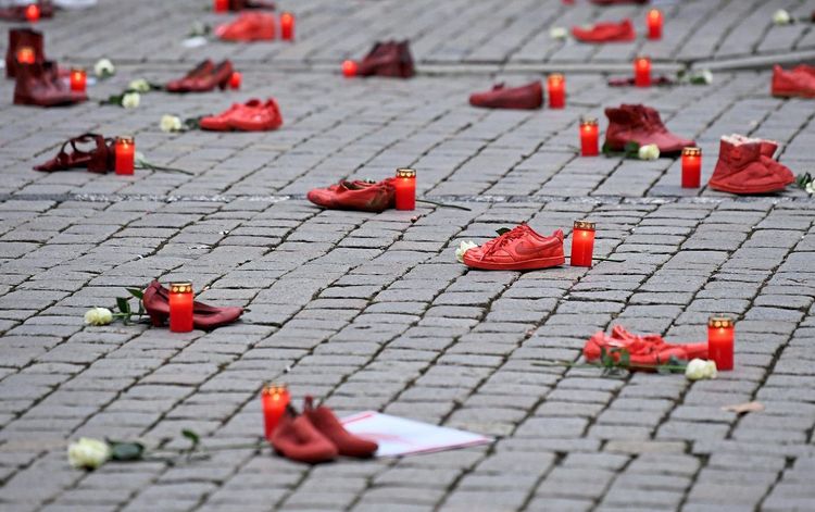Schuhe und eine Gedenkkerze daneben. So wird bei einer Aktion ermordeter Frauen gedacht. 