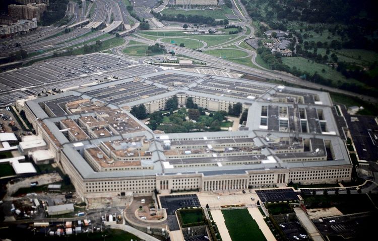 Luftaufnahme des Pentagon, dem Hauptquartier des US-Militärs, mit seiner charakteristischen fünfeckigen Bauweise, umgeben von Straßen, Parkplätzen und Grünflächen.