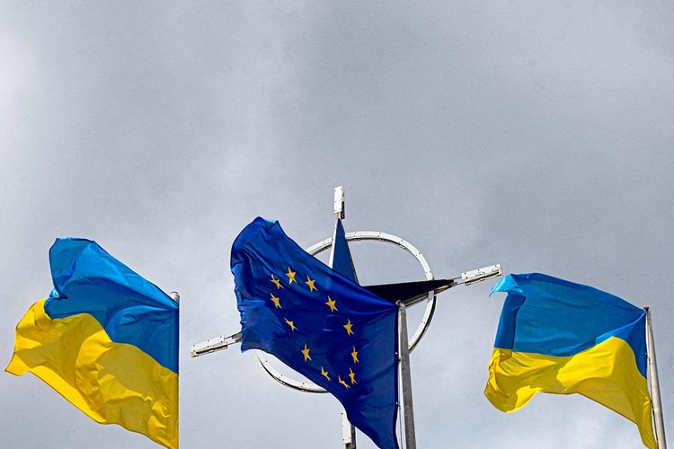 EU Flagge und Ukraine Flagge, dahinter das Symbol der NATO