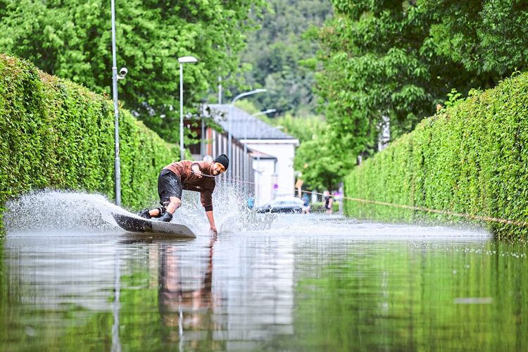 Ein Wakeboarder auf einer überfluteten Straße beim Strandbad Klagenfurt.