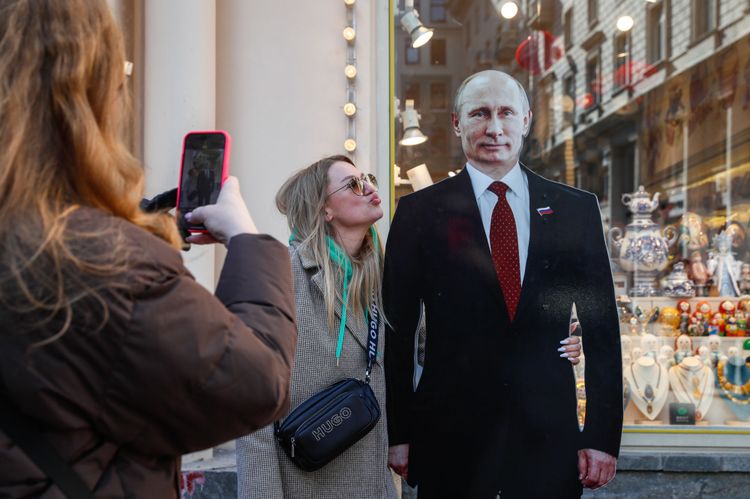 Frauen machen Handyfotos mit Putin-Pappfigur