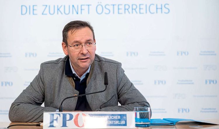FPÖ-Bildungssprecher Hermann Brückl sitzt hinter einem Mikrofon, vor dem ein Schild mit der Aufschrift 