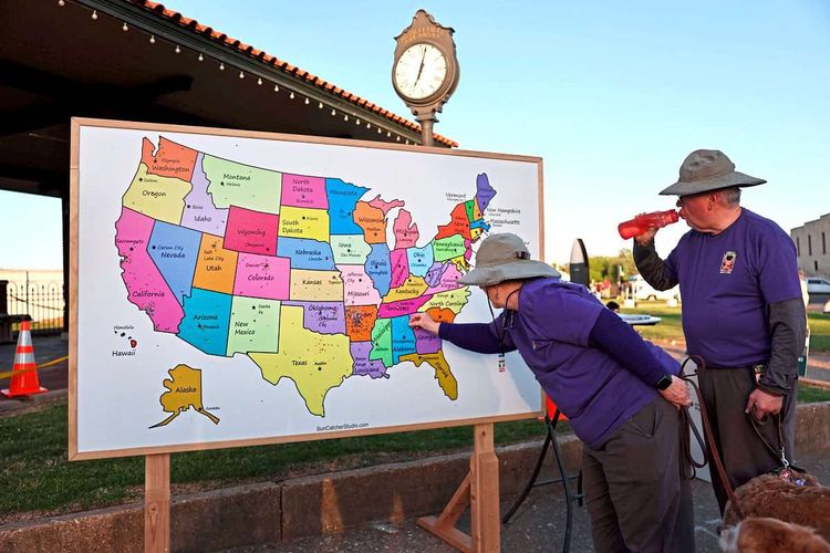 Touristen markieren den Pfad der totalen Sonnenfinsternis auf einer USA-Karte.