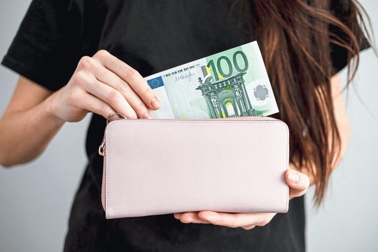 Young woman takes out money euro banknotes from a leather wallet. Close up. High quality photo
