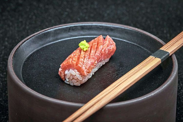 Ein Stück Sushi auf einem schwarzen Teller