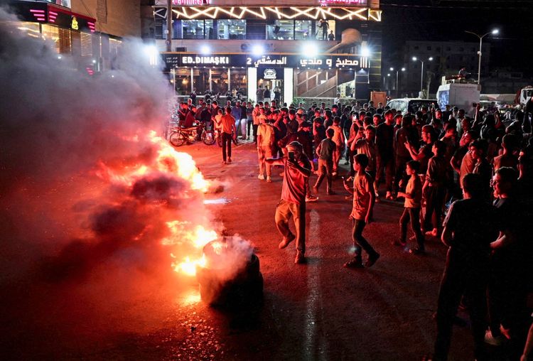 Protestierende verbrennen Reifen und blockieren eine Straße bei Nacht als Protest gegen steigende Kraftstoffpreise auf der Autobahn zwischen Aleppo und der Türkei in Syrien, 13. September 2026. Im Hintergrund sind Menschenansammlungen und ein beleuchtetes Gebäude zu sehen.