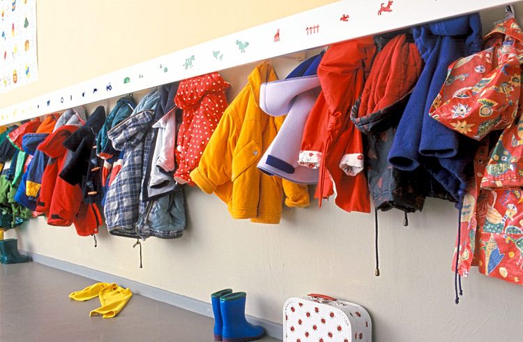 Kinderjacken hängen auf einer Garderobenleiste im Kindergarten.