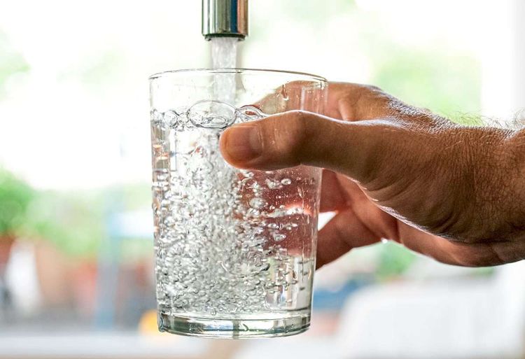 Ein Mann füllt Leitungswasser in ein Glas.