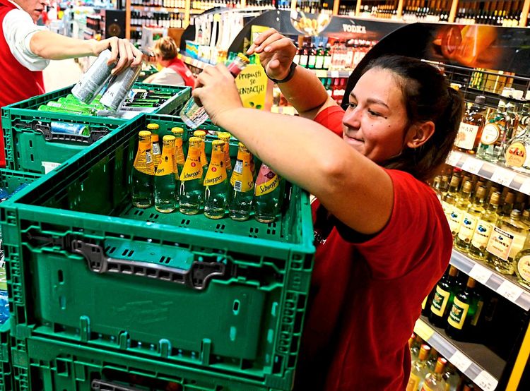 Supermarktarbeiterin schlichtet Flaschen in eine Plastikkiste
