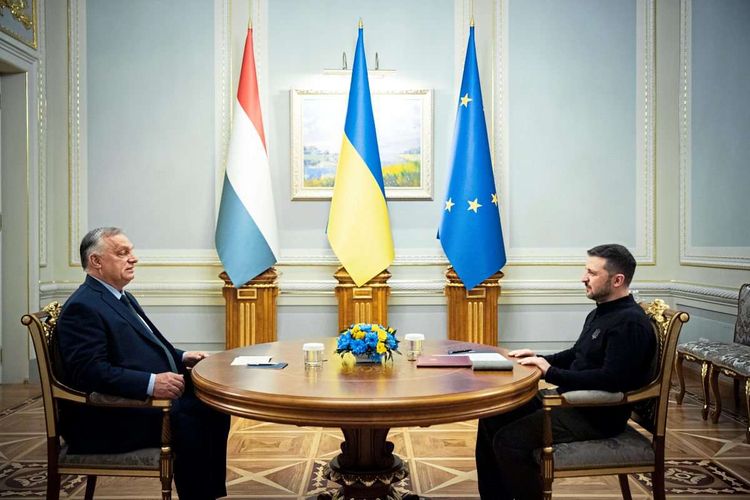 Viktor Orbán und Wolodymyr Selenskyj sitzen einander an einem runden Tisch gegenüber.